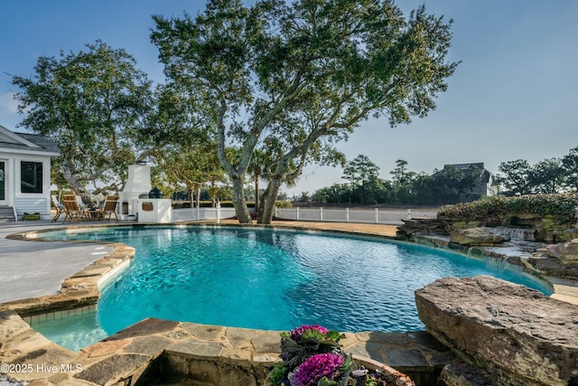 view of pool featuring a patio, a fenced in pool, fence, and an outdoor stone fireplace