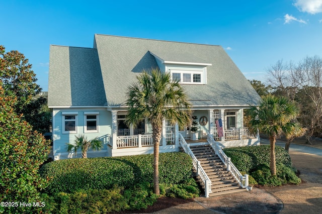 view of front of home featuring stairs, roof with shingles, and covered porch