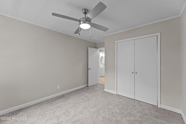 unfurnished bedroom with crown molding, light colored carpet, a closet, and ceiling fan