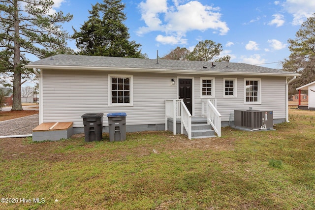 rear view of house featuring central AC unit and a lawn