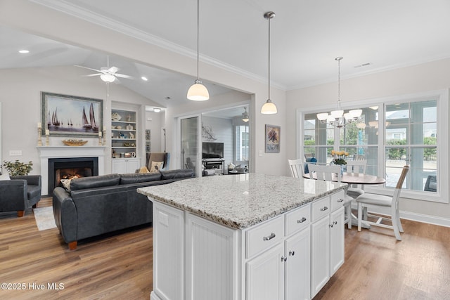 kitchen with white cabinetry, decorative light fixtures, light hardwood / wood-style floors, and a center island