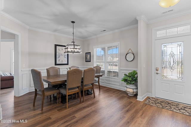 dining area with crown molding, dark wood-type flooring, and an inviting chandelier