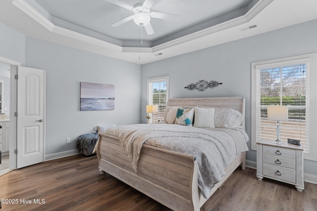 bedroom featuring dark wood-type flooring, ornamental molding, a raised ceiling, and ceiling fan