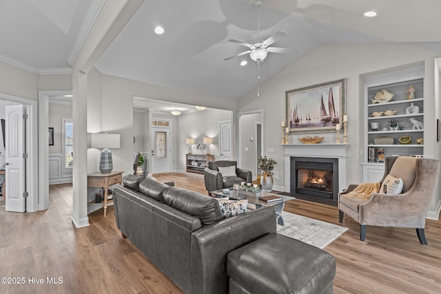 living room featuring crown molding, lofted ceiling, wood-type flooring, and built in shelves