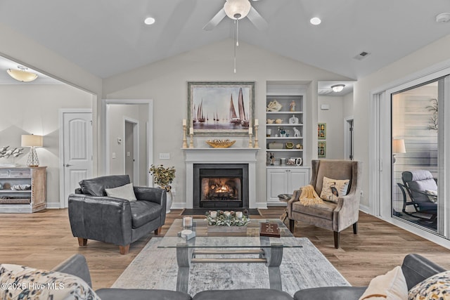 living room with built in shelves, light hardwood / wood-style flooring, and vaulted ceiling