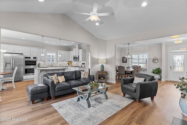 living room featuring crown molding, sink, a healthy amount of sunlight, and light wood-type flooring