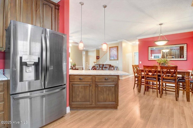 kitchen with a peninsula, ornamental molding, light wood-type flooring, and stainless steel fridge