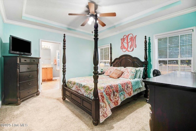 bedroom featuring light carpet, a tray ceiling, connected bathroom, and ornamental molding