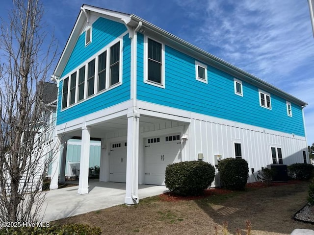 rear view of house with a carport, driveway, a garage, and central air condition unit