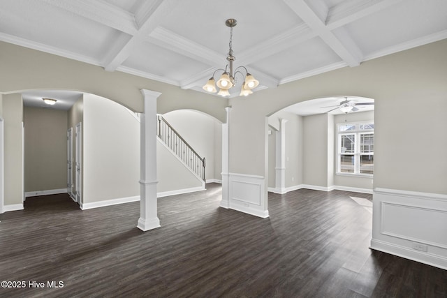 unfurnished dining area featuring coffered ceiling, ornamental molding, dark hardwood / wood-style flooring, ceiling fan with notable chandelier, and beamed ceiling