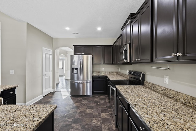 kitchen featuring stainless steel appliances, light stone countertops, and a textured ceiling