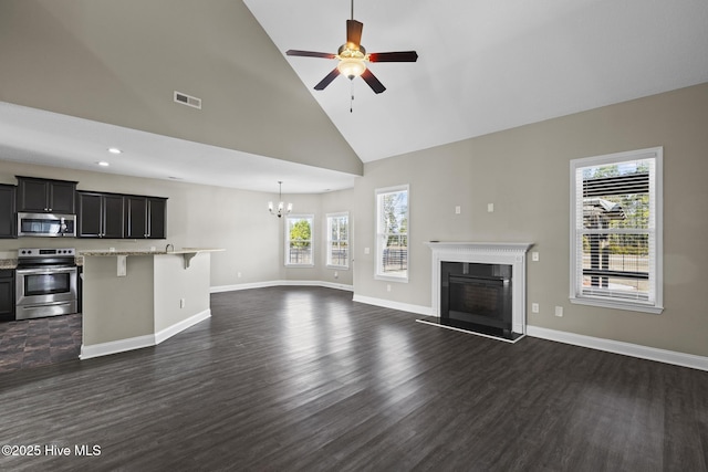 unfurnished living room featuring dark hardwood / wood-style flooring, ceiling fan with notable chandelier, and high vaulted ceiling