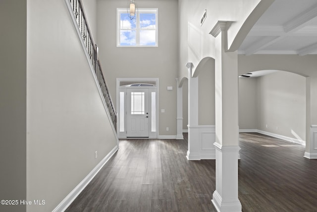 entrance foyer with beam ceiling, a towering ceiling, coffered ceiling, dark hardwood / wood-style flooring, and ornate columns