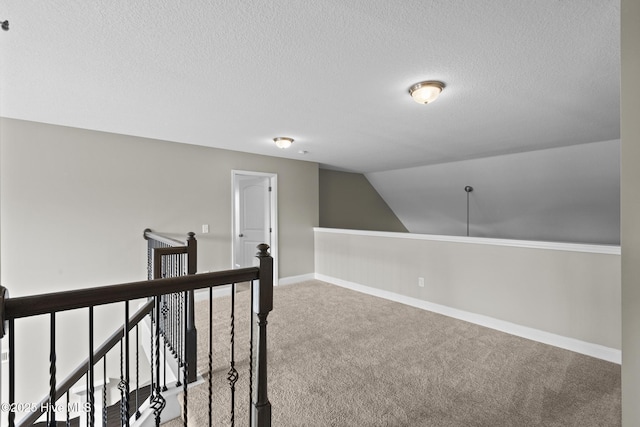 hall featuring lofted ceiling, a textured ceiling, and carpet