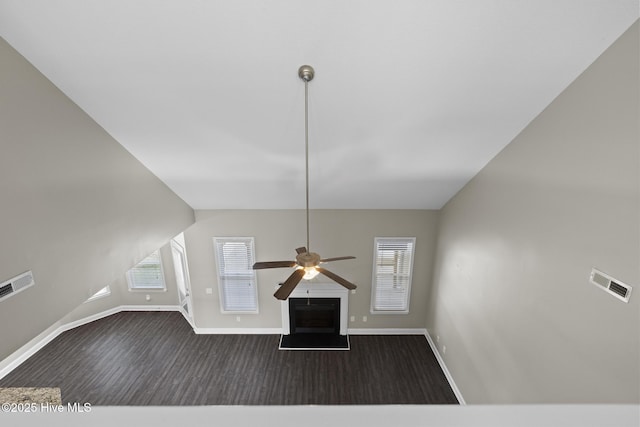 unfurnished living room with dark wood-type flooring, ceiling fan, and vaulted ceiling