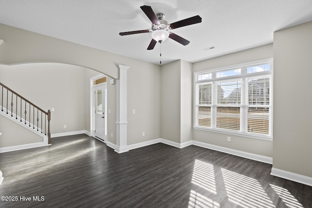 unfurnished living room featuring ceiling fan, decorative columns, dark hardwood / wood-style floors, and a textured ceiling