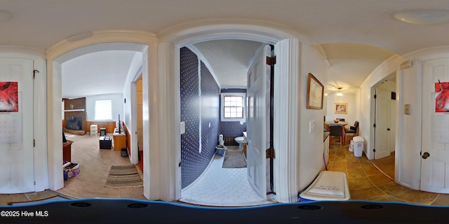 hall featuring arched walkways and light tile patterned floors