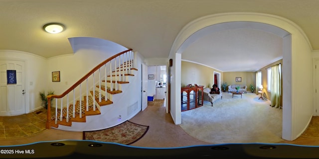 entrance foyer featuring baseboards, arched walkways, stairs, crown molding, and carpet flooring