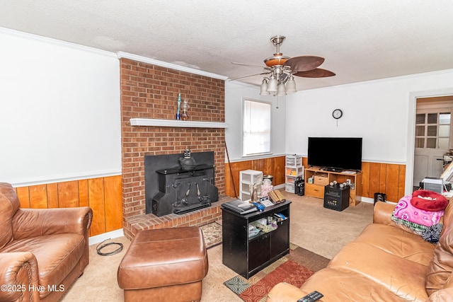 living room featuring light carpet, ornamental molding, a textured ceiling, and wainscoting