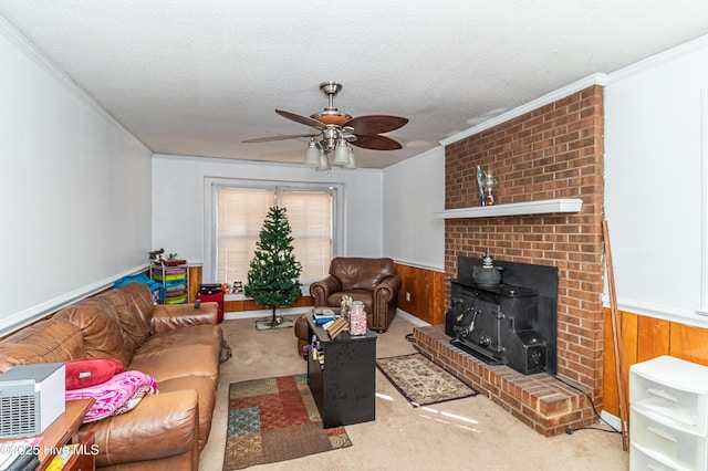 carpeted living area with a textured ceiling, wooden walls, a wainscoted wall, ornamental molding, and a wood stove