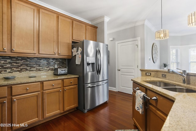 kitchen featuring stainless steel refrigerator with ice dispenser, sink, light stone counters, decorative light fixtures, and backsplash