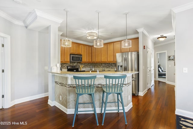 kitchen featuring dark wood-type flooring, a breakfast bar, appliances with stainless steel finishes, ornamental molding, and kitchen peninsula