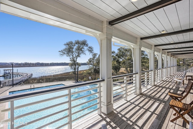 wooden terrace featuring a water view and a fenced in pool