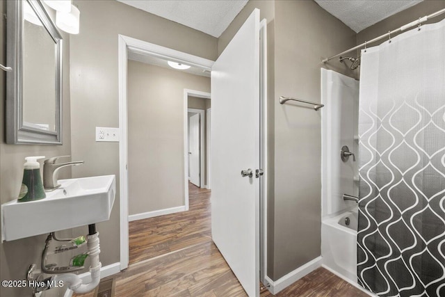 bathroom featuring shower / bathtub combination with curtain, hardwood / wood-style floors, and a textured ceiling