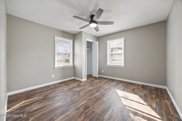 unfurnished bedroom with multiple windows, dark hardwood / wood-style flooring, a closet, and a textured ceiling