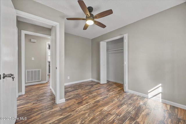 unfurnished bedroom featuring dark wood-type flooring, ceiling fan, a closet, and a textured ceiling