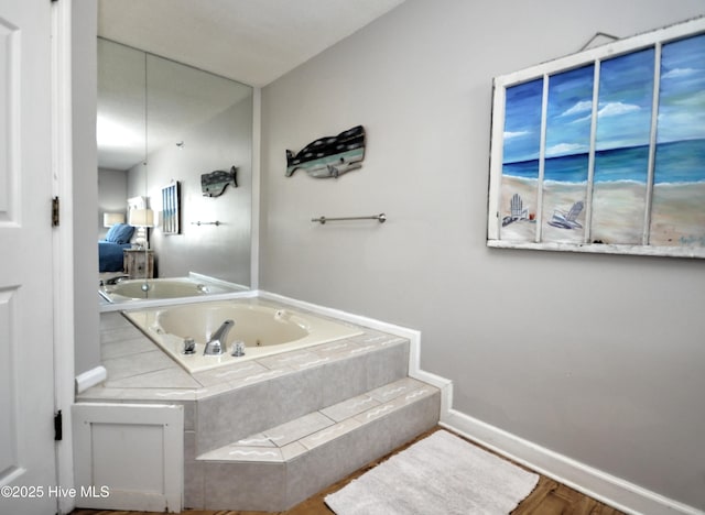 bathroom with tiled tub and wood-type flooring