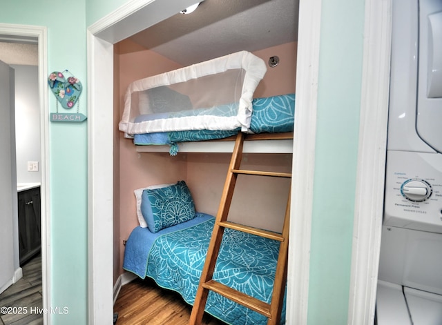 bedroom featuring stacked washer / drying machine and wood-type flooring