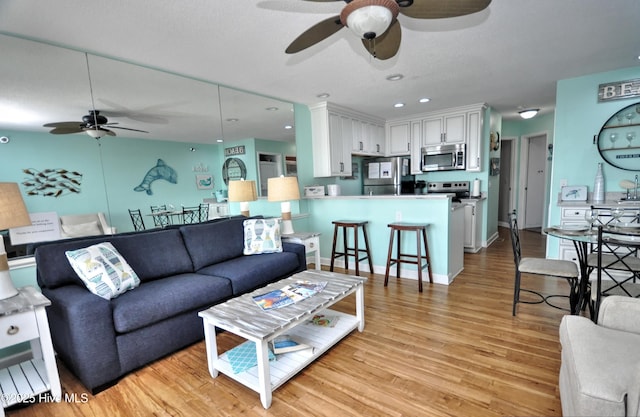 living room with ceiling fan and light wood-type flooring