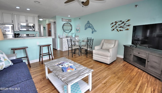 living room with ceiling fan and light hardwood / wood-style floors