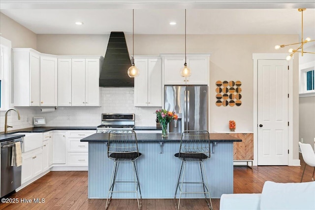 kitchen with range hood, white cabinets, stainless steel appliances, and a sink