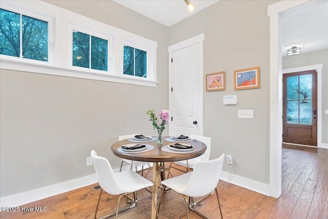 dining space with baseboards and wood-type flooring