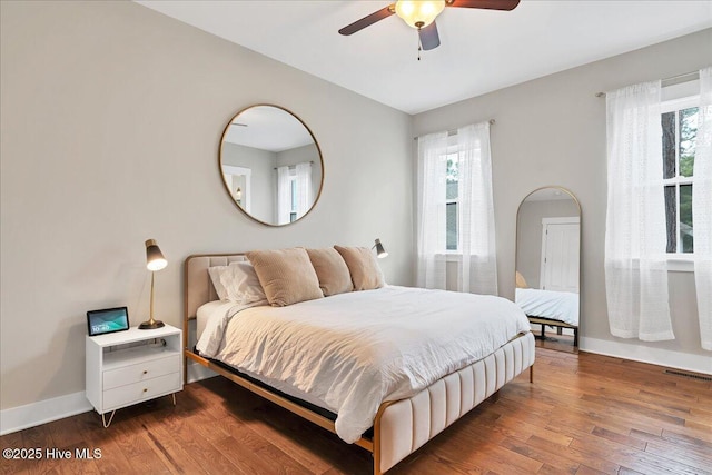 bedroom with visible vents, a ceiling fan, baseboards, and wood finished floors