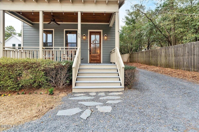 property entrance with a porch, ceiling fan, and fence