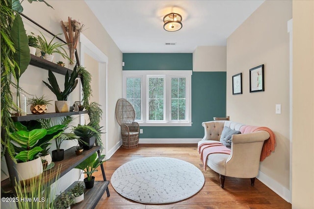 living area featuring visible vents, baseboards, and wood finished floors