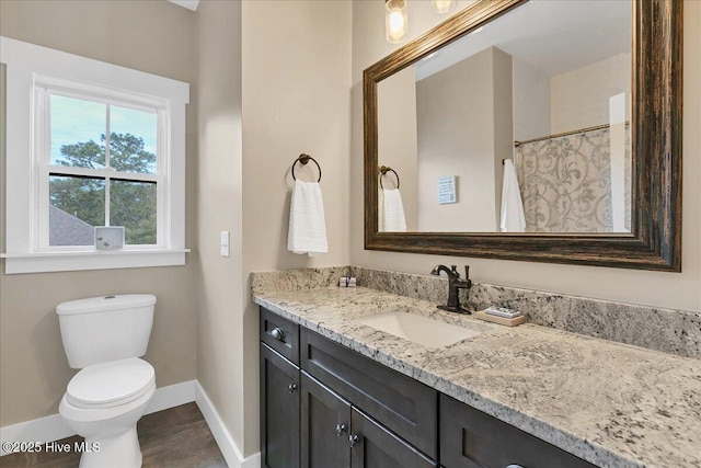 bathroom featuring toilet, vanity, and baseboards