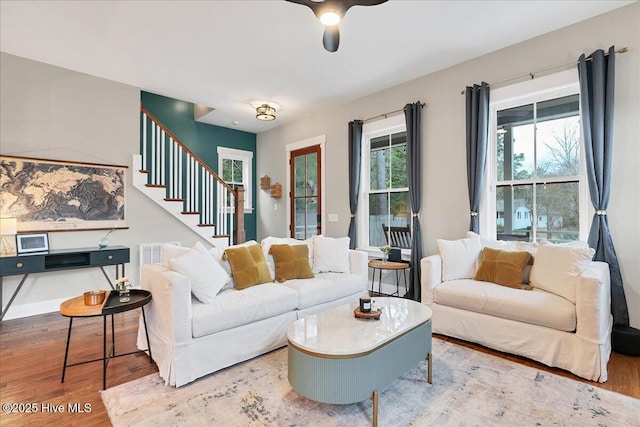 living area with stairs, ceiling fan, and wood finished floors