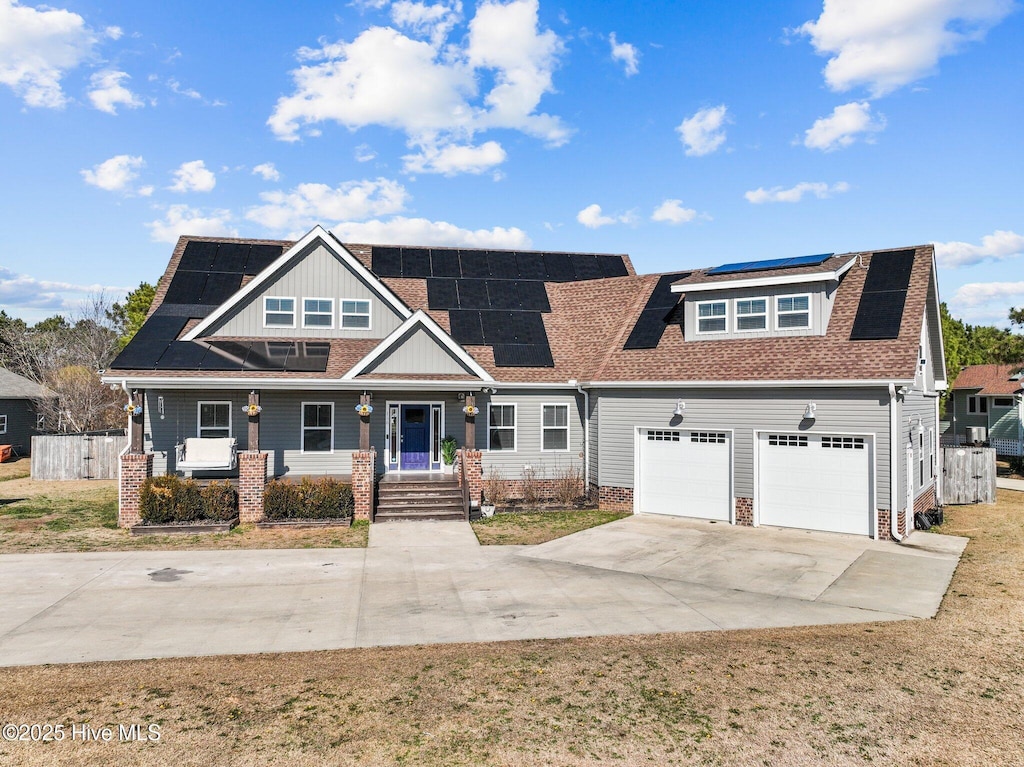 view of front facade with a porch, a front yard, and solar panels