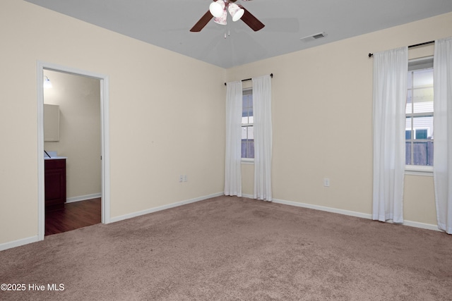 empty room featuring a wealth of natural light, ceiling fan, carpet, and visible vents