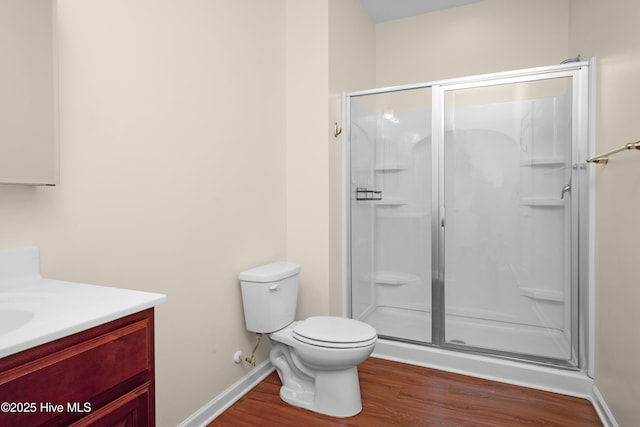 full bathroom featuring vanity, wood finished floors, toilet, baseboards, and a stall shower