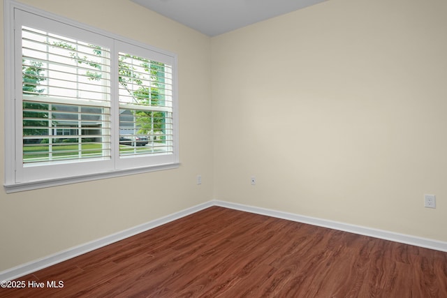 spare room featuring baseboards and wood finished floors
