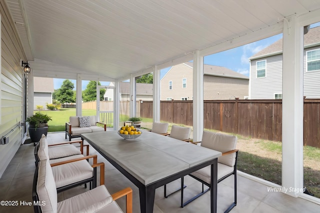 sunroom / solarium with wood walls, outdoor dining area, and lofted ceiling