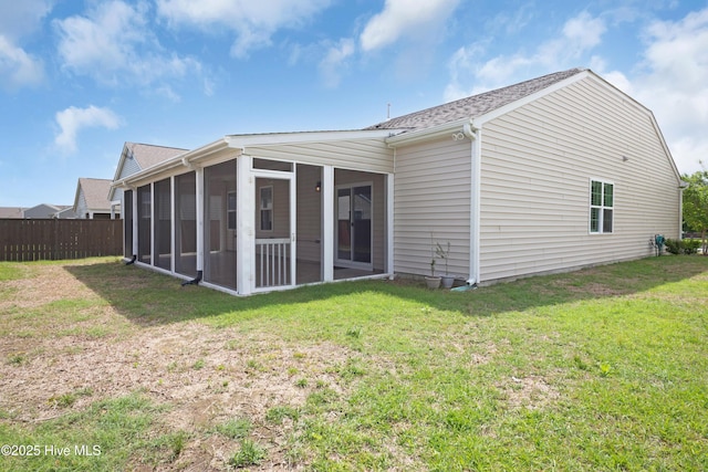back of property with a yard, roof with shingles, fence, and a sunroom