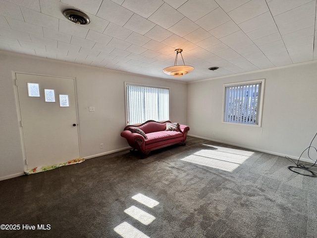 unfurnished living room featuring crown molding and dark carpet