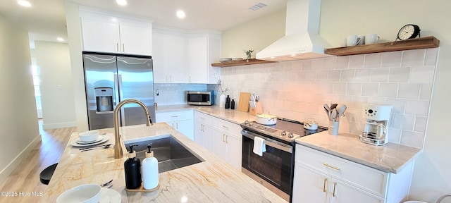 kitchen featuring sink, white cabinetry, light stone counters, appliances with stainless steel finishes, and range hood