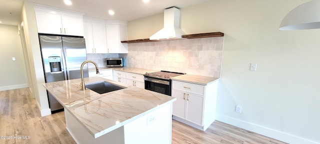 kitchen with sink, white cabinets, stainless steel appliances, a center island with sink, and wall chimney exhaust hood